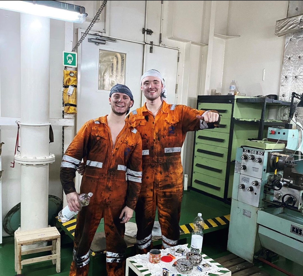 Two Stream Marine Careers Engine Cadets in the engine room of a ship in orange overalls.